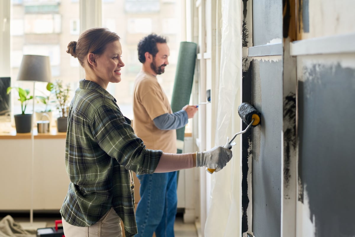 Couple painting a living room wall during an interior improvement project