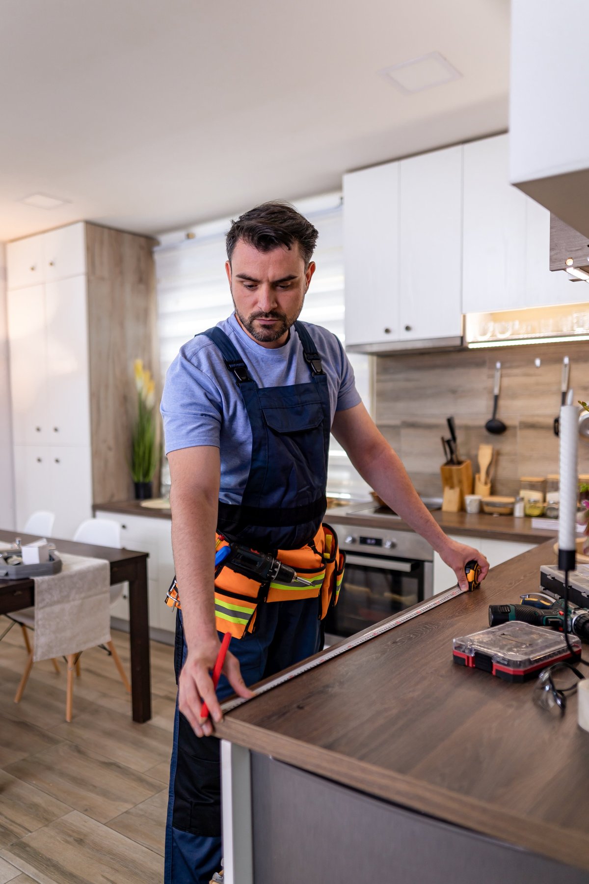 Carpenter measuring and fitting cabinetry in a contemporary kitchen